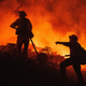 Firefighters coordinate efforts at a burning property while battling the Fairview Fire on Monday, Sept. 5, 2022, near Hemet, California.